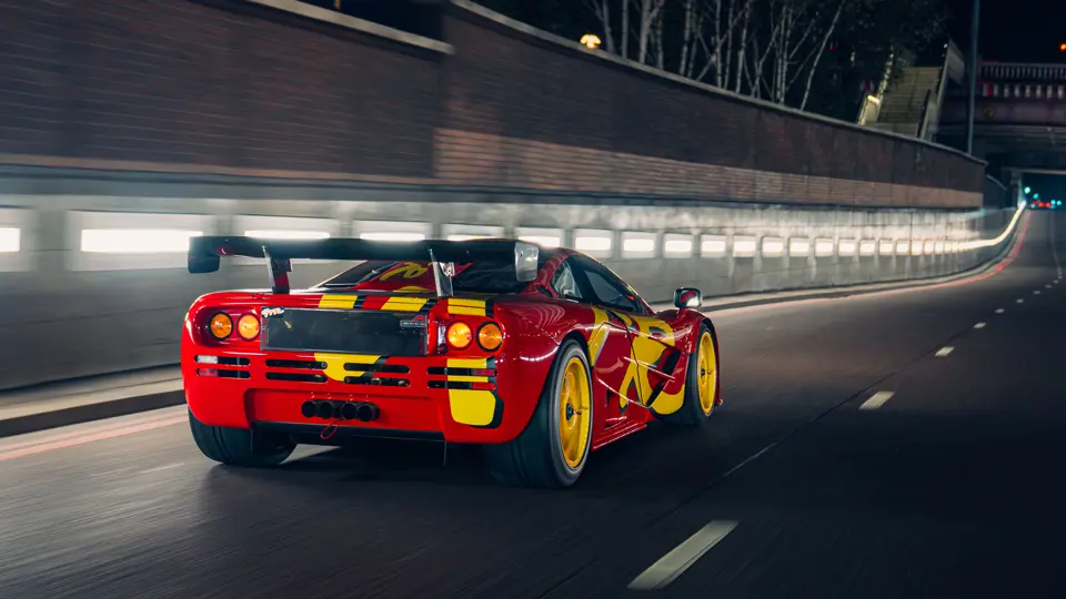 The red and yellow 1996 McLaren F1 GTR chassis 10R driving through an illuminated city tunnel