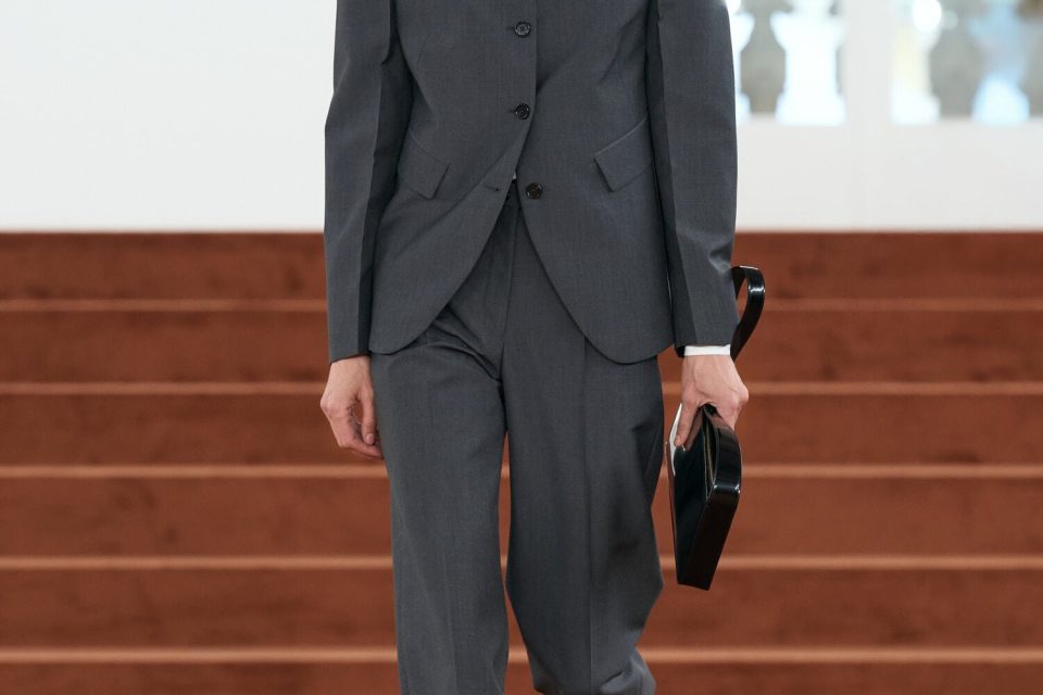 A model wearing charcoal tailoring on the rust-coloured runway at the Jil Sander Autumn/Winter 2026 show in Milan