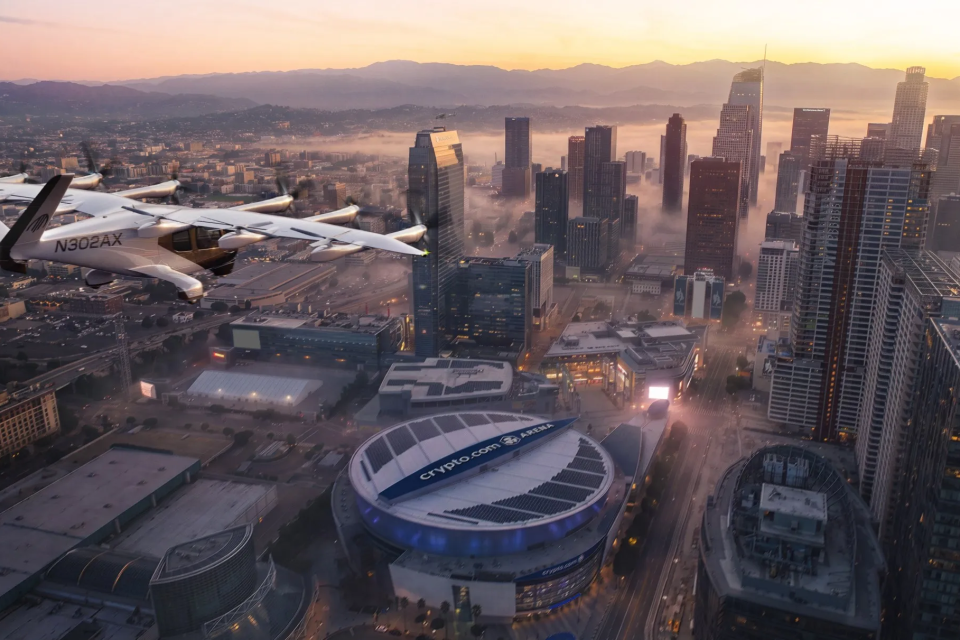 Archer Midnight electric air taxi flying above downtown Los Angeles and the L.A. LIVE arena district at sunset.