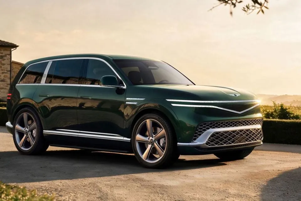 Green Genesis GV90 electric flagship SUV in a front three-quarter view on a stone terrace at sunset.
