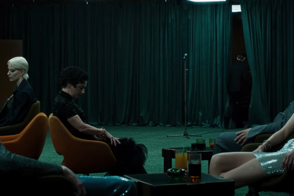 Gucci Primavera campaign film scene with guests seated around a dark green curtained performance space