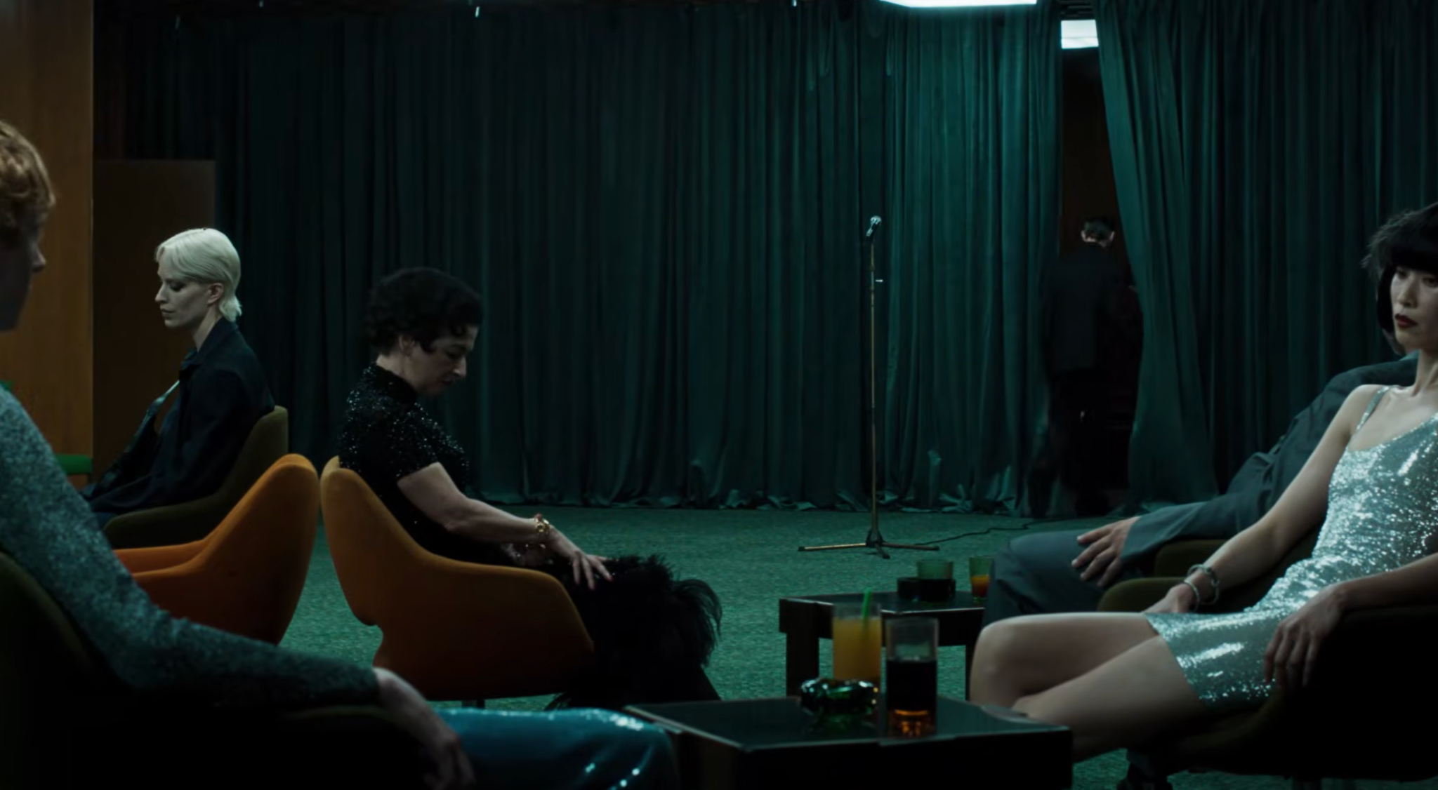Gucci Primavera campaign film scene with guests seated around a dark green curtained performance space
