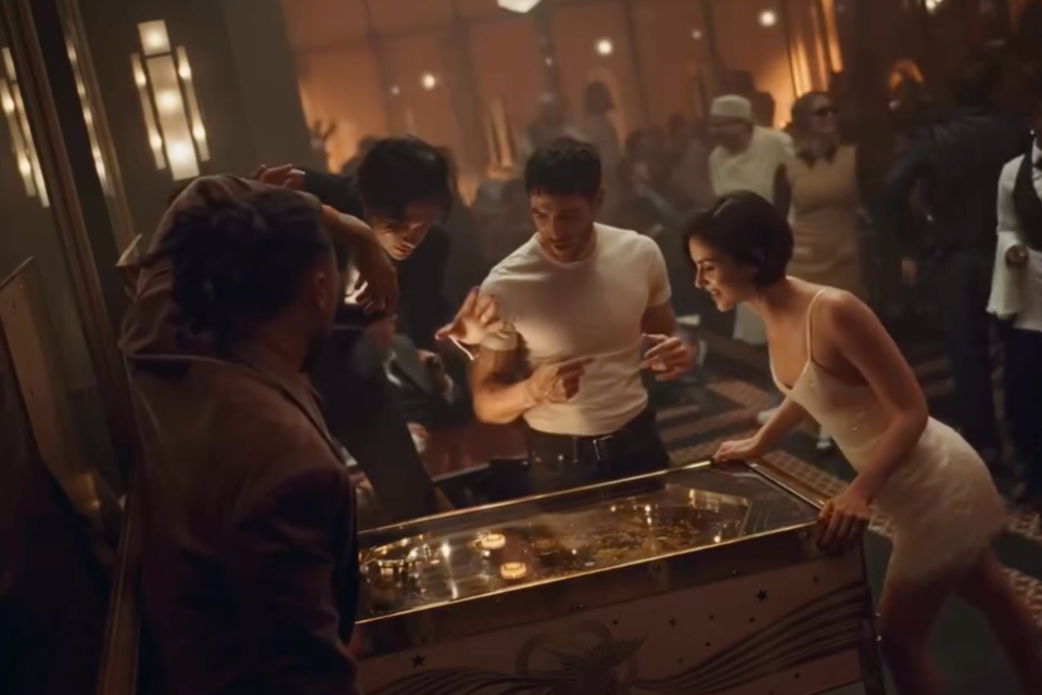 Gracie Abrams and guests gathered around a pinball machine in the CHANEL COCO MADEMOISELLE CRUSH ABSOLU campaign