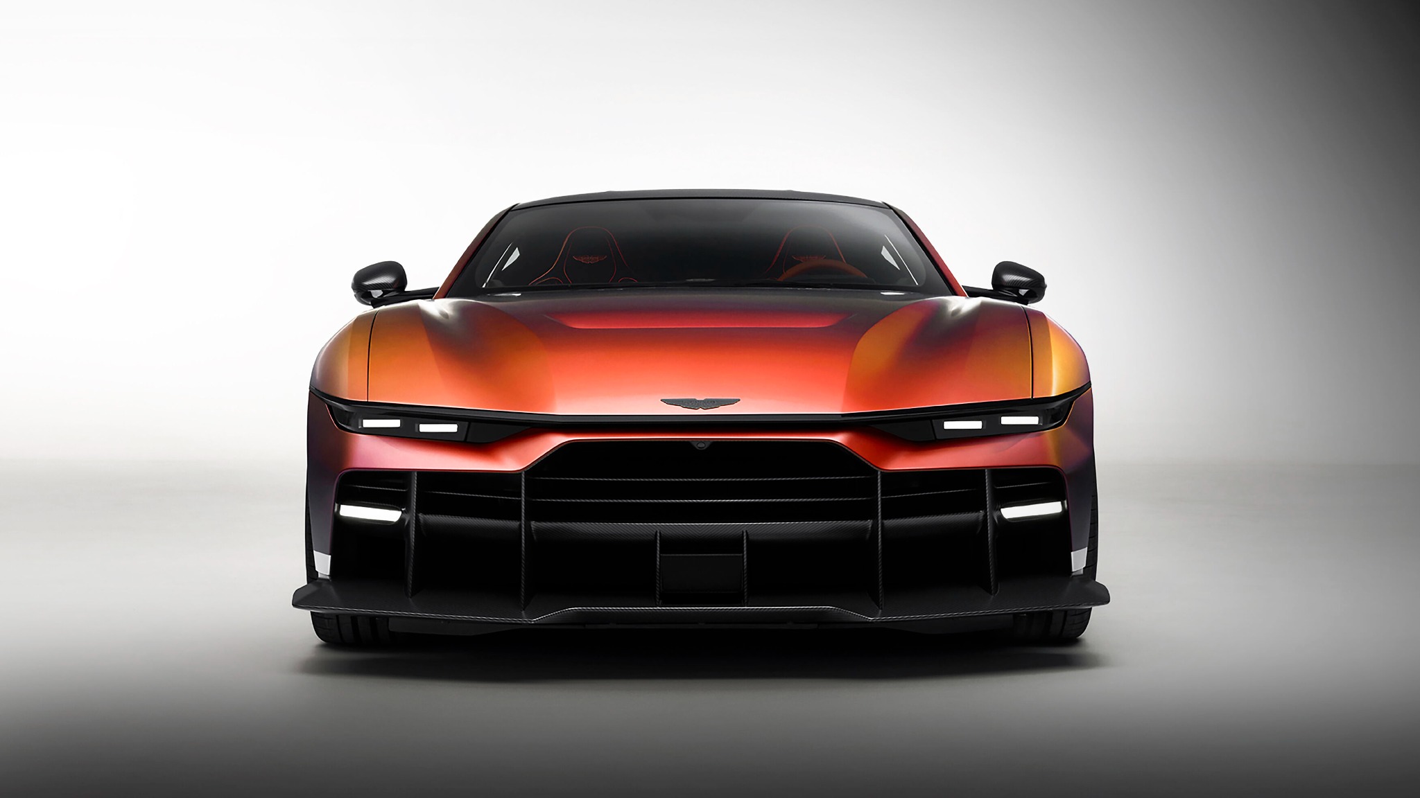 Front view of the Aston Martin Valen in Satin Andromeda Red, showing its slim headlamps and deep carbon fibre front aero treatment.