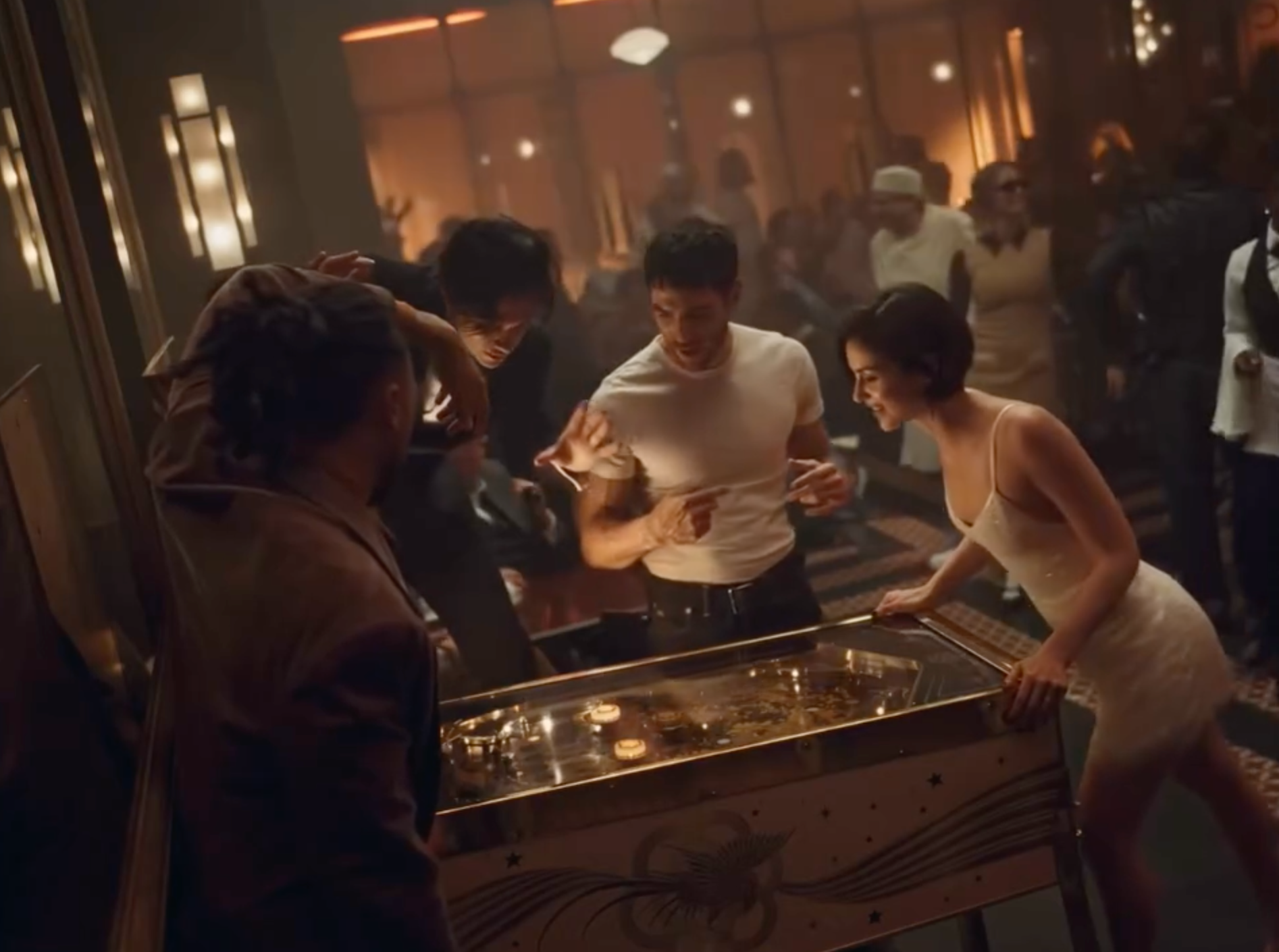 Gracie Abrams and guests gathered around a pinball machine in the CHANEL COCO MADEMOISELLE CRUSH ABSOLU campaign