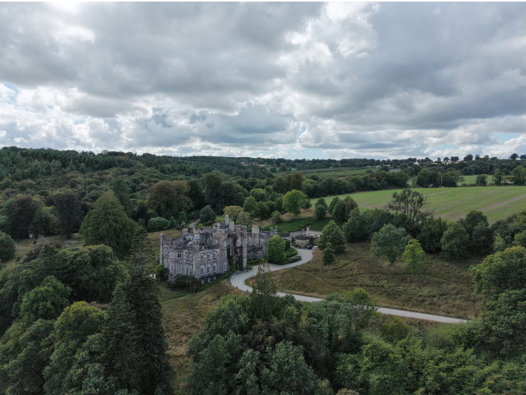 Strancally Castle beside the River Blackwater, surrounded by woodland and rolling Irish countryside.