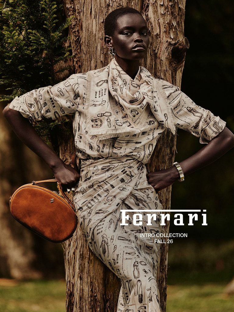 Athiec Geng wearing Ferrari’s Officina print with a tan leather bag in the Pre-Fall 2026 campaign.