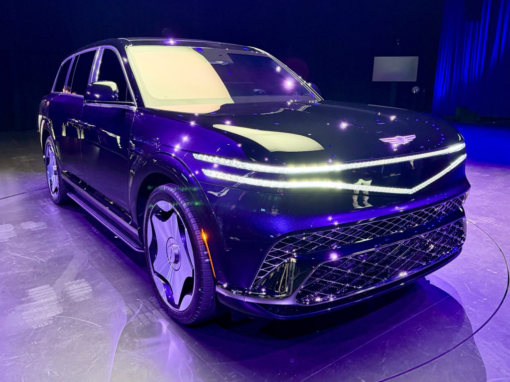 Genesis GV90 displayed under blue lighting during its global unveiling.