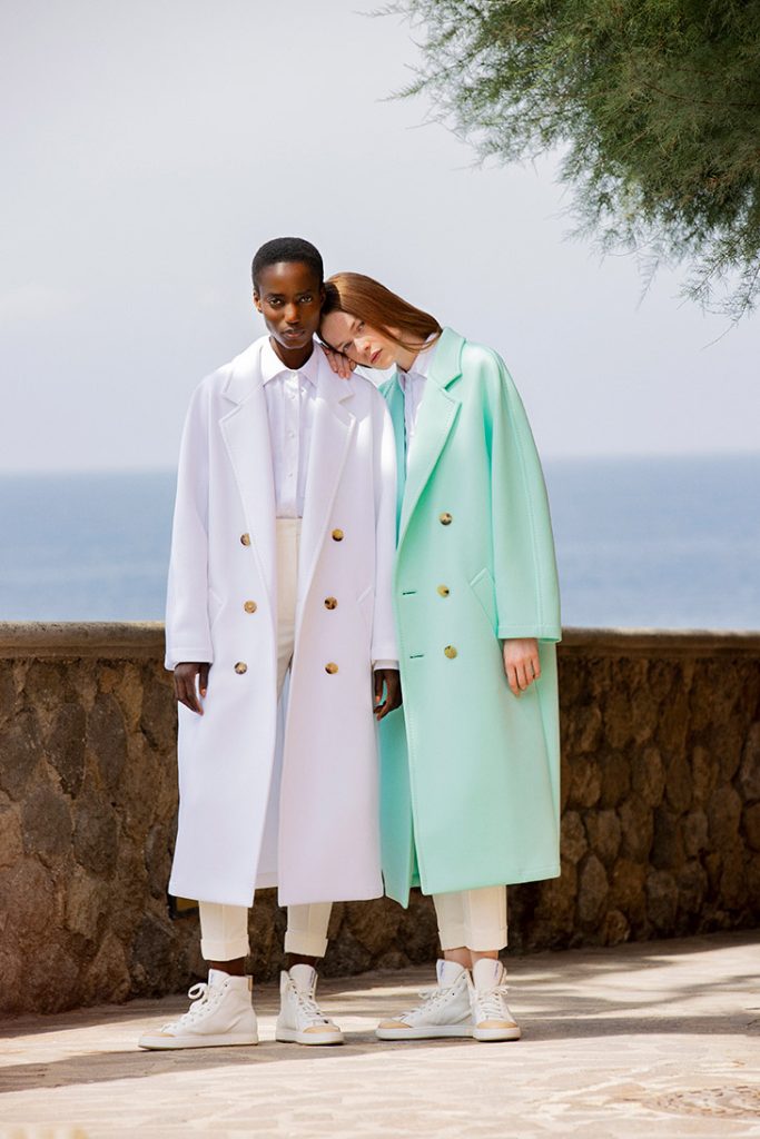Two models wearing white and mint Max Mara 101801 Light coats beside the sea.