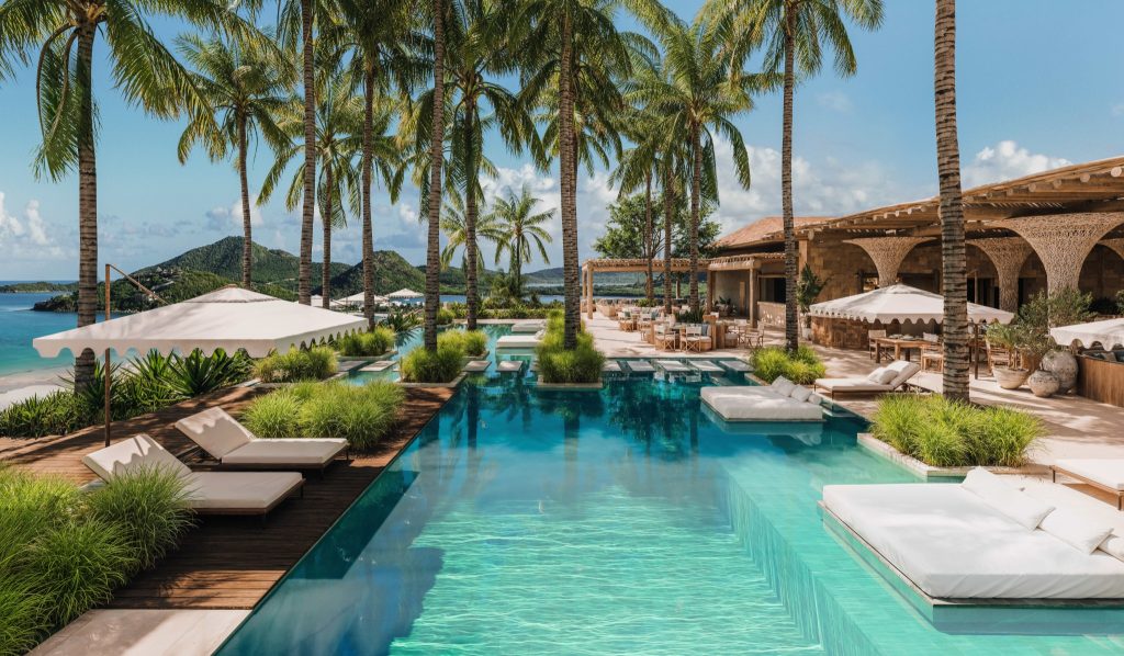 Pool and palm-lined social spaces at Nikki Beach Resort and Spa Antigua overlooking the Caribbean coastline.