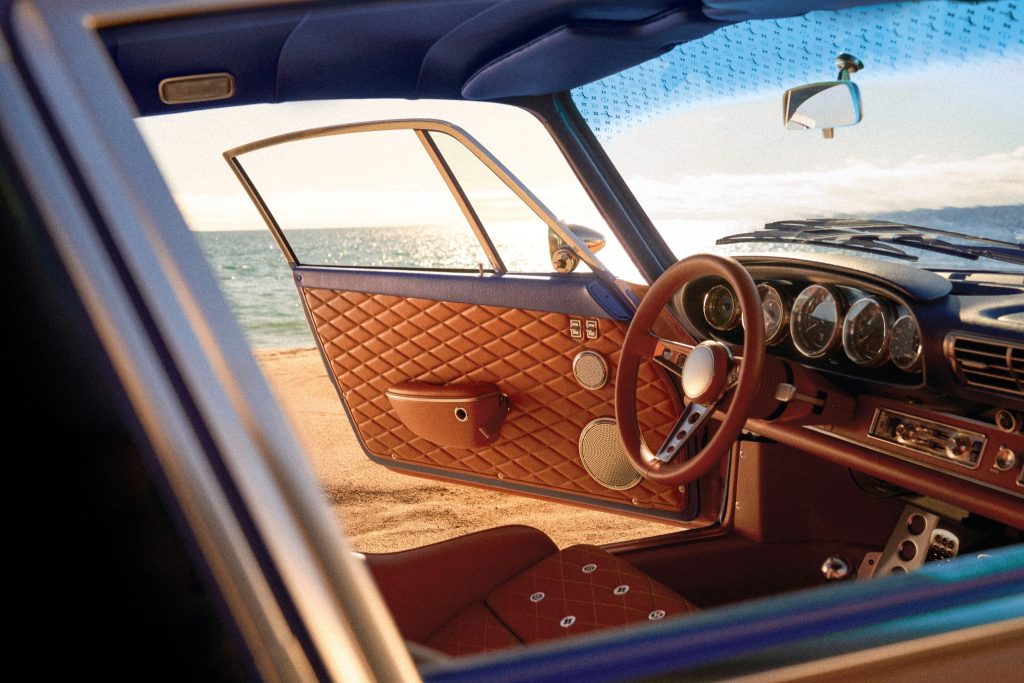 Interior detail of the saffron Louis Vuitton and Singer Classic showing quilted leather door trim and analogue instrumentation beside the sea.