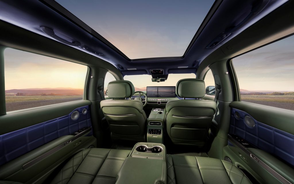 Rear cabin view of the Genesis GV90 beneath its panoramic glass roof, looking towards the front seats.