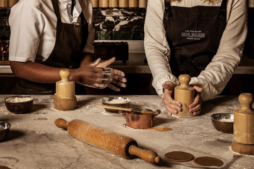 A guest shaping pastry beside a Pie Maker during a masterclass at The Pie Room, Rosewood London