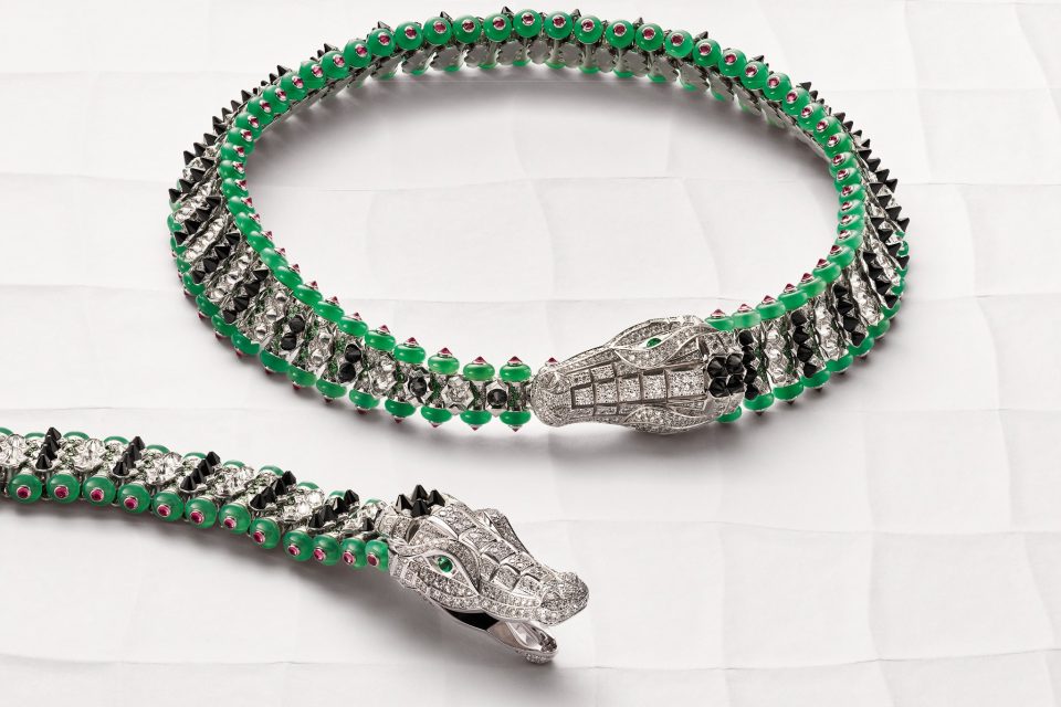 Cartier crocodile bracelet and necklace arranged on a pale sculptural surface, with diamonds, black onyx, green chrysoprase and rubellite details.