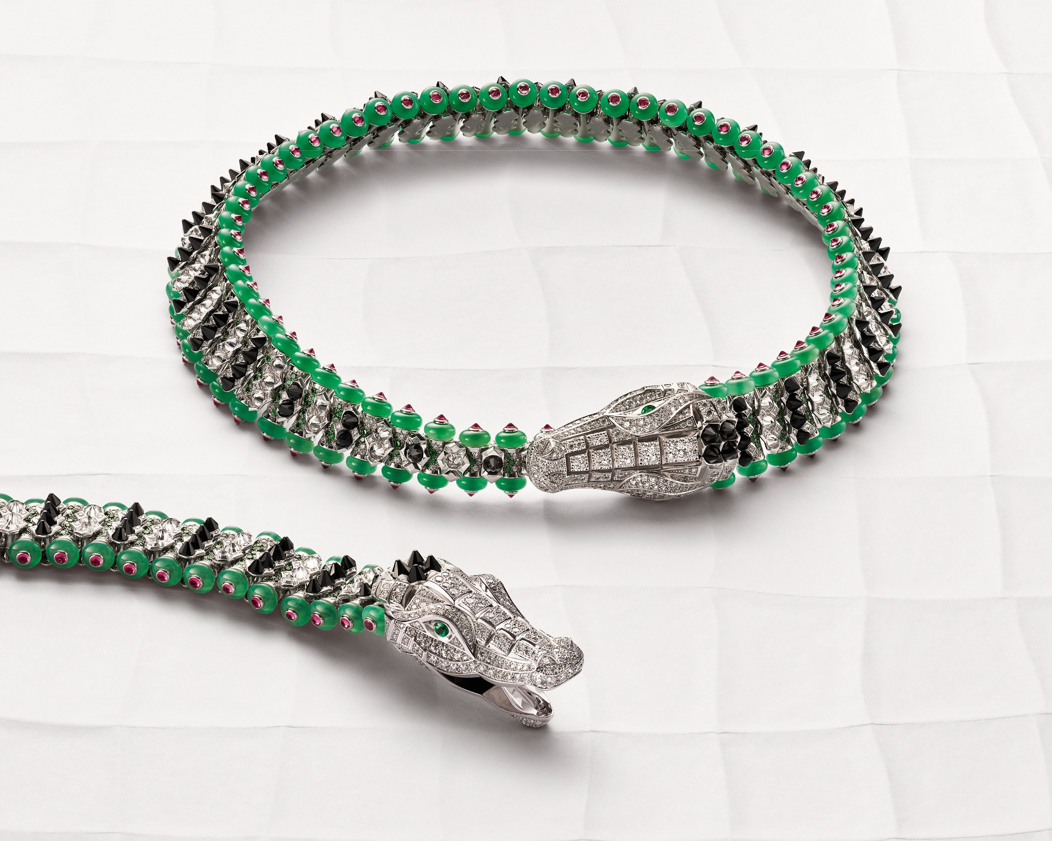 Cartier crocodile bracelet and necklace arranged on a pale sculptural surface, with diamonds, black onyx, green chrysoprase and rubellite details.