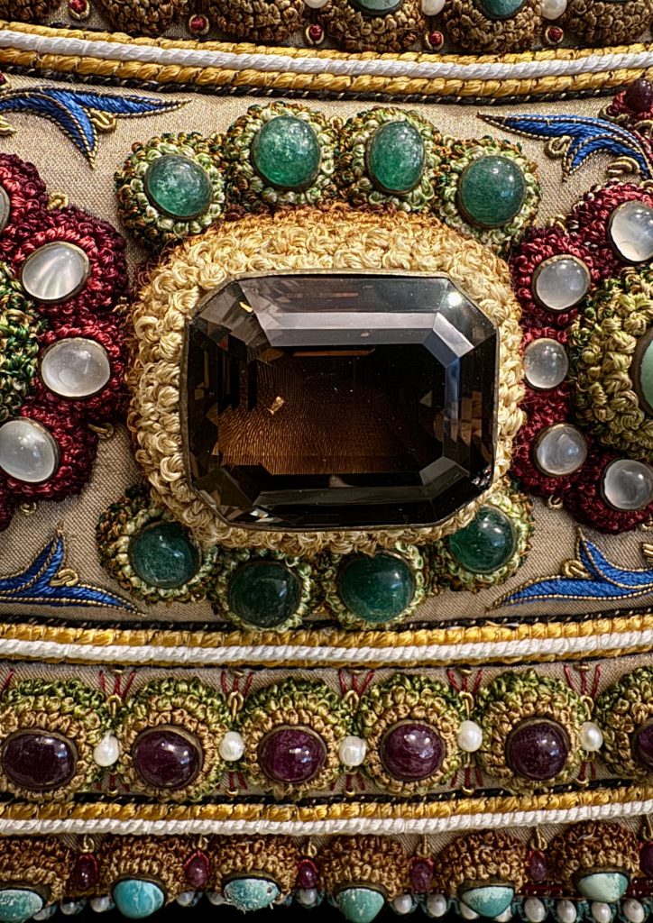 Large faceted centrepiece stone within an elaborate jewelled surround in The Vase.