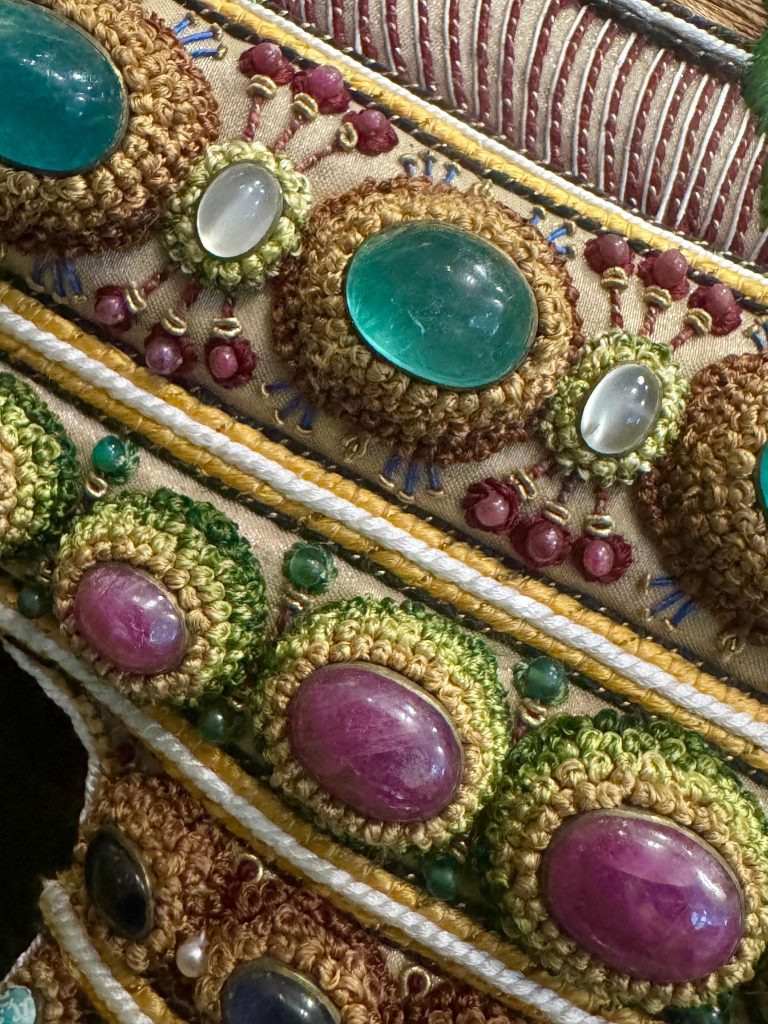 Oblique view of emerald cabochons and gemstones set within the embroidered vessel of The Vase.