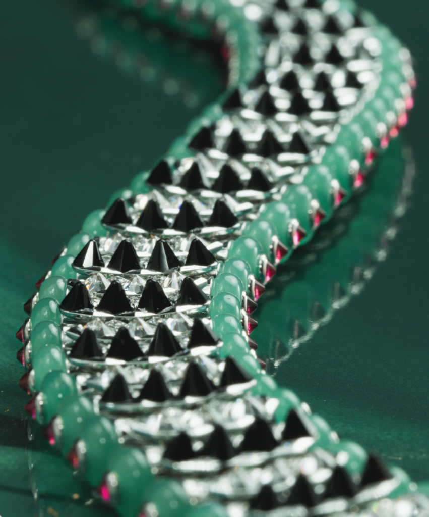 Macro view of Cartier crocodile jewellery showing geometric diamond scales, black onyx spikes, green chrysoprase edging and flashes of rubellite.