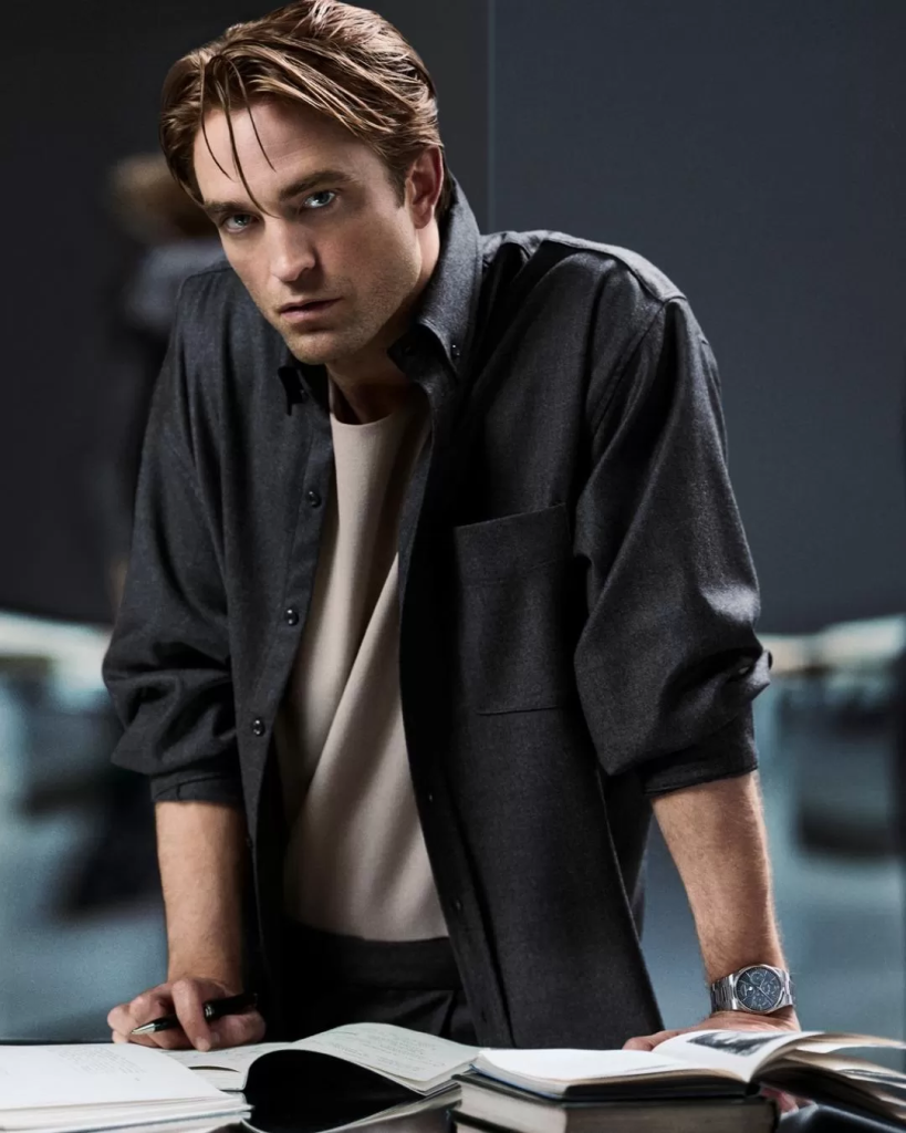 Robert Pattinson leaning over open books while wearing the stainless-steel Jaeger-LeCoultre Master Control Chronometre Perpetual Calendar.