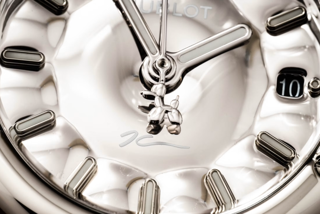 Macro detail of the silver dial, date aperture and miniature Balloon Dog counterweight.