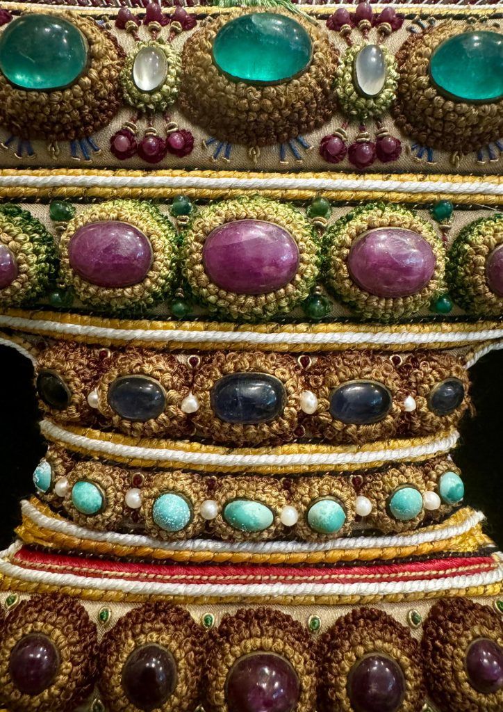 Bands of emerald cabochons and gemstones within the gold embroidery of The Vase.