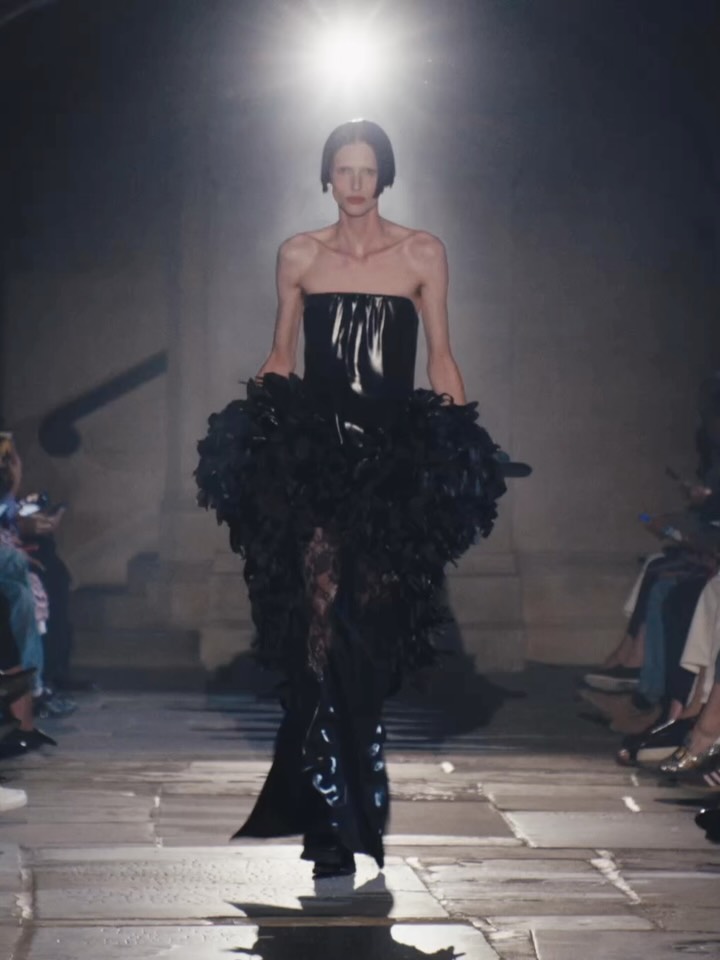 Model in black heritage lace and lacquered satin with feather embellishment detail