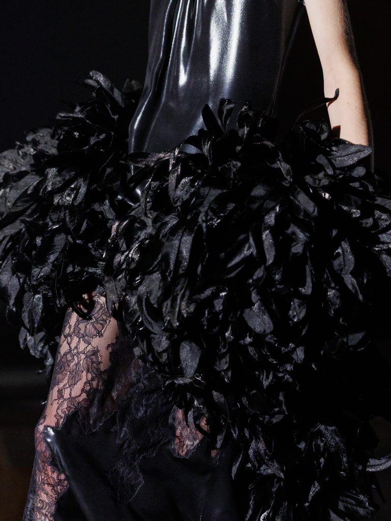 Model in dramatic black lacquered satin with feathered details