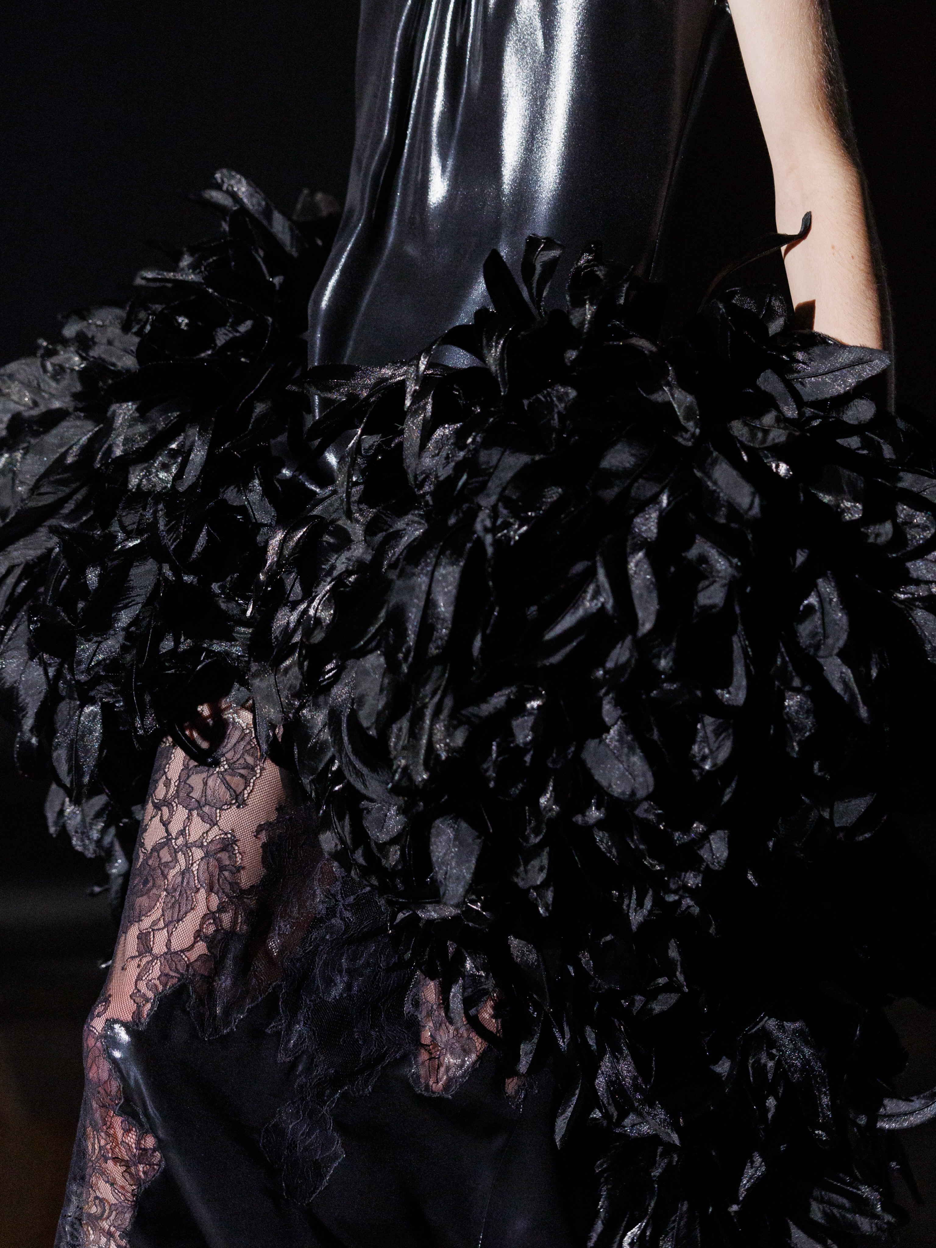 Model in dramatic black lacquered satin with feathered details