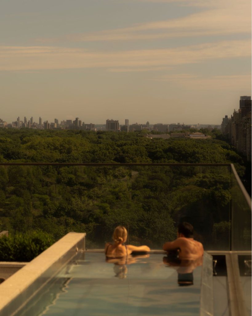 Elegantly appointed guest suite with floor to ceiling windows overlooking autumn foliage and cityscape