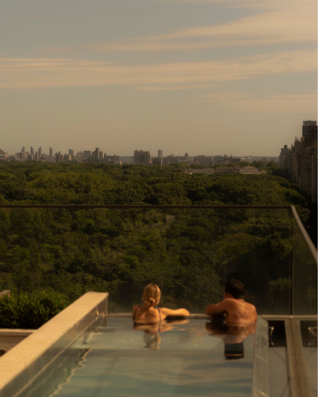 Elegantly appointed guest suite with floor to ceiling windows overlooking autumn foliage and cityscape