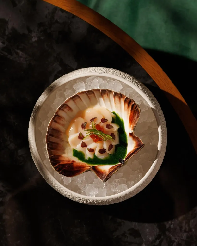 Close detail of the Viera Tataki showing the precisely seared scallop with delicate garnishes and pickled radish elements
