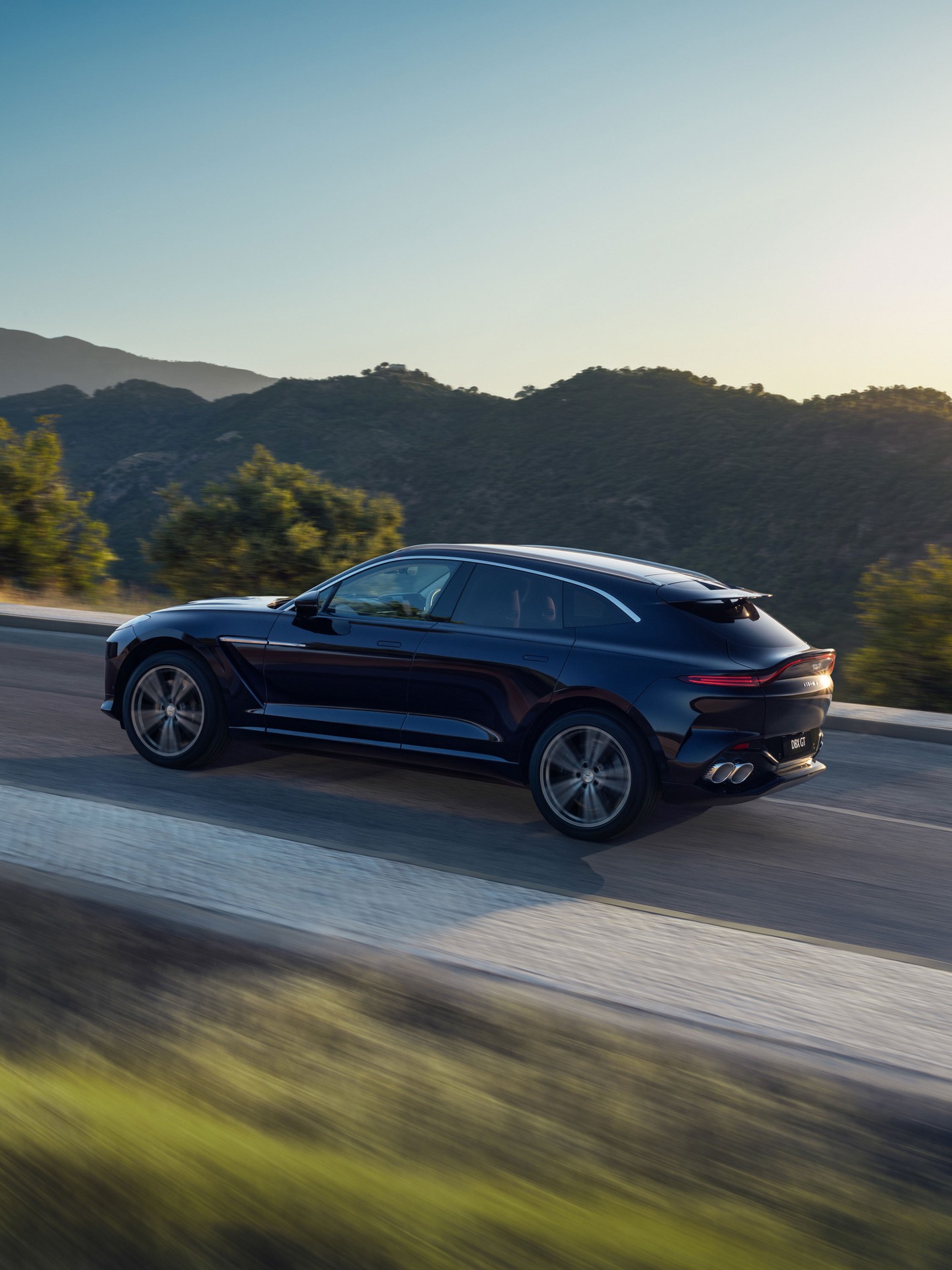Aston Martin DBX GT in motion, showcasing its commanding presence and refined SUV silhouette