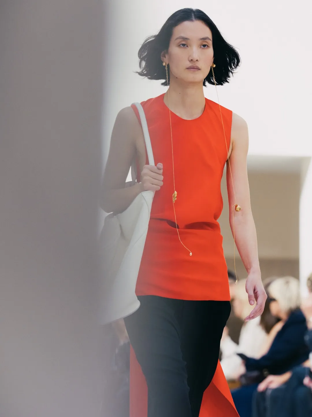 Full-length ensemble showcasing architectural shoulders and cascading coral-toned fabric