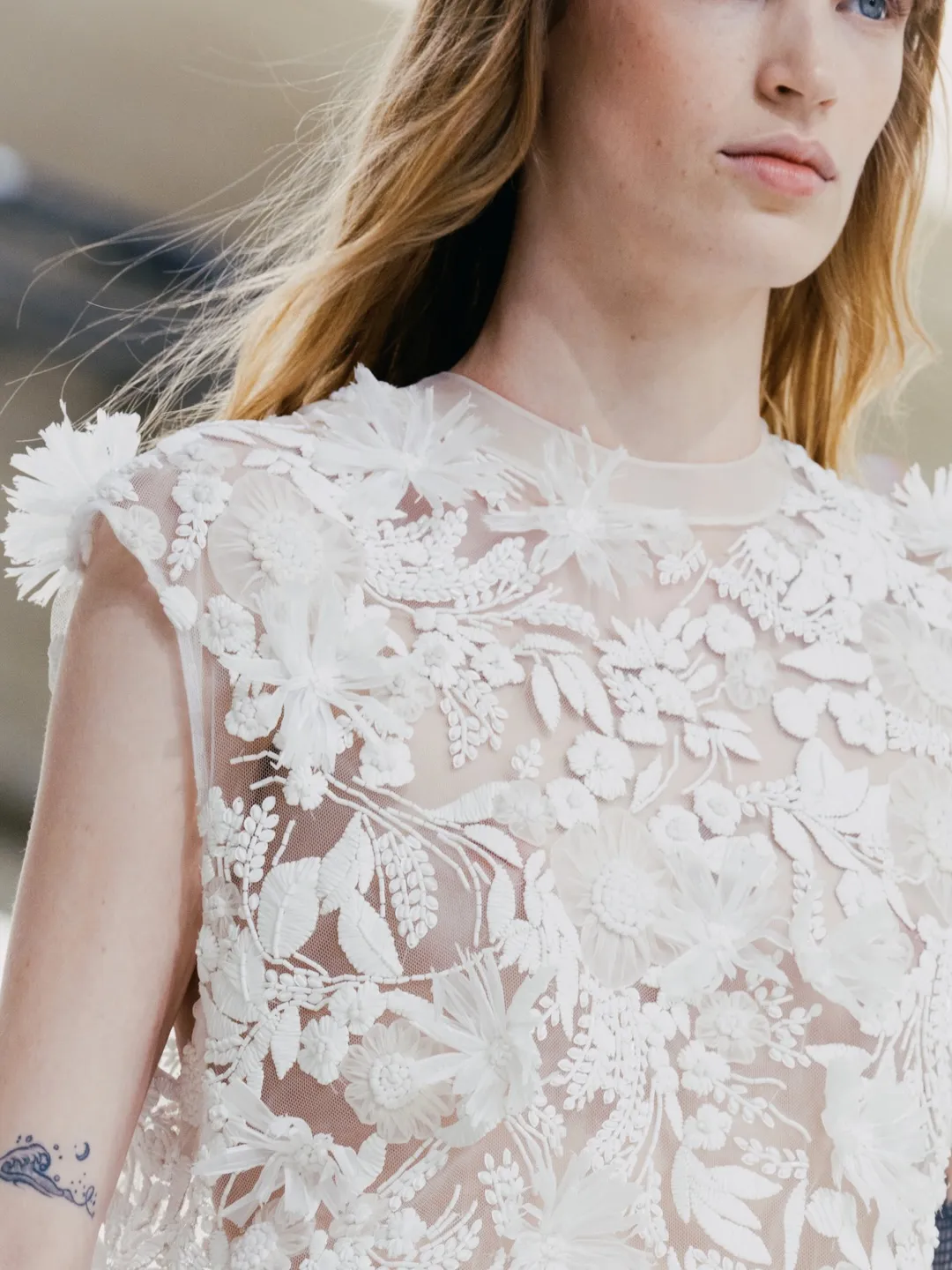 Model in cream and terracotta colour-blocked piece with sculptural sleeve construction