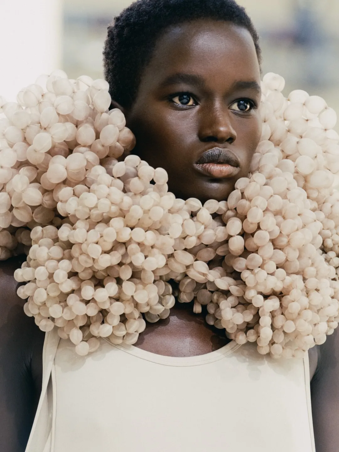 Model wearing coral-toned draped gown from Balenciaga Summer 27 Collection