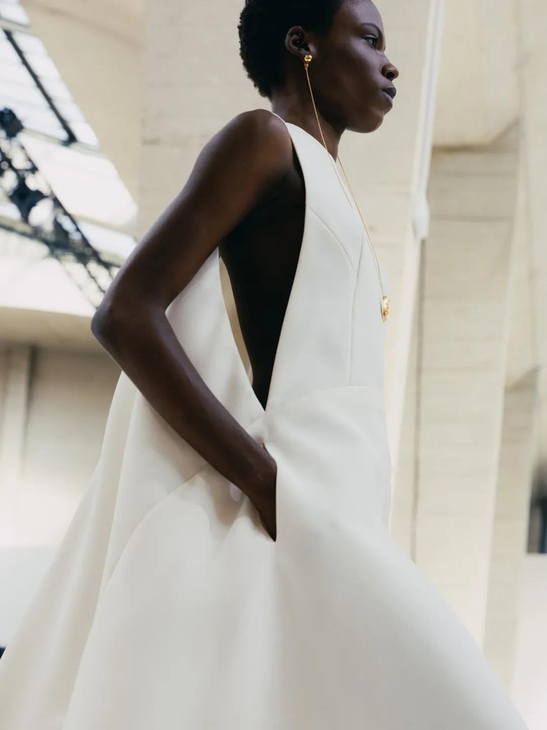 Model in layered coral and amber ensemble demonstrating chromatic juxtaposition and movement