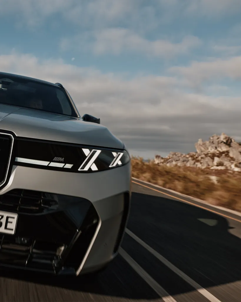 BMW X5 M60e xDrive in motion on an open road demonstrating dynamic performance capability