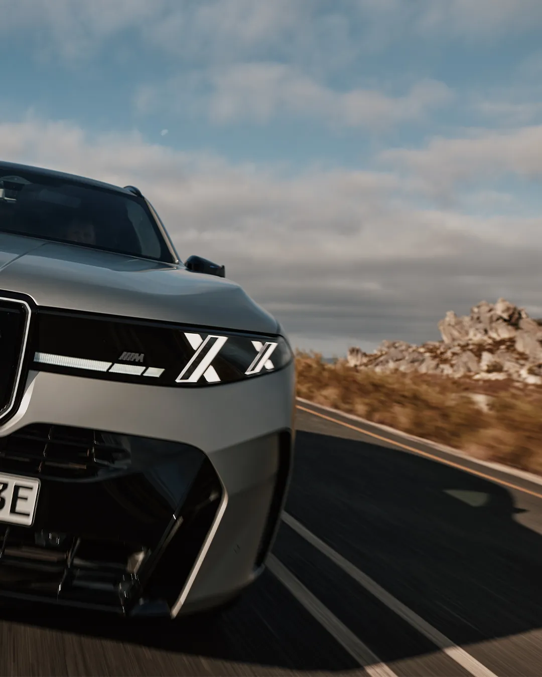 BMW X5 M60e xDrive in motion on an open road demonstrating dynamic performance capability