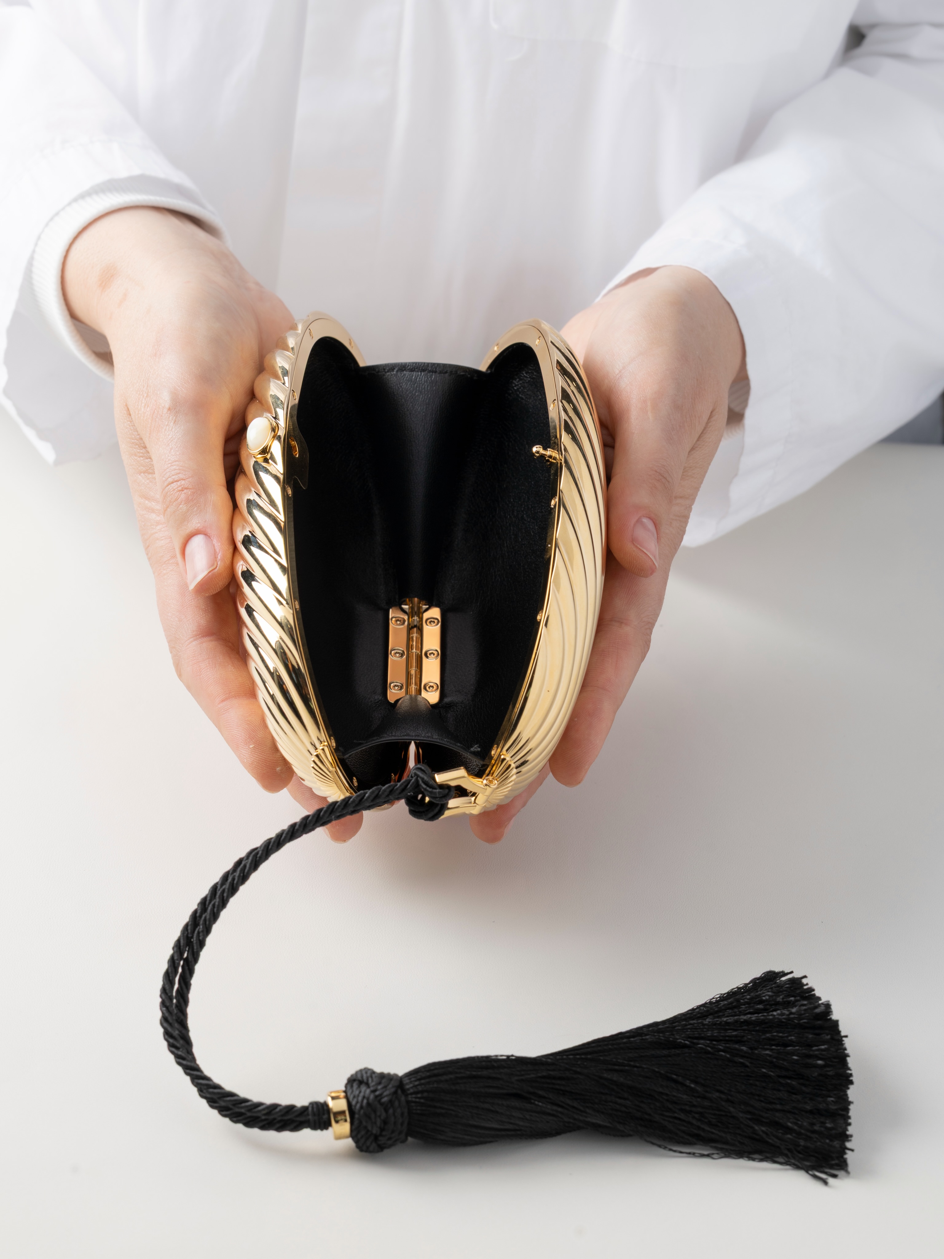 The clutch held in hand, emphasising its scale and tactile quality as a wearable jewelled object