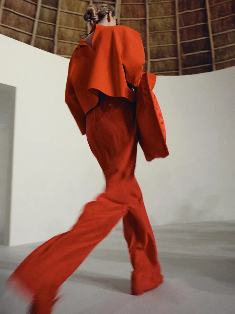 Full length view of model in soft taupe silhouette with architectural draping
