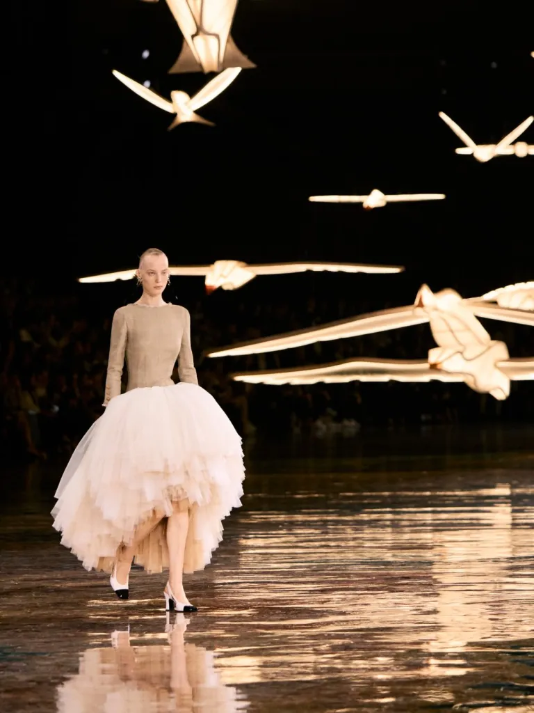 Full-length view of a silhouette combining cinched tailoring with flowing, transparent fabrics