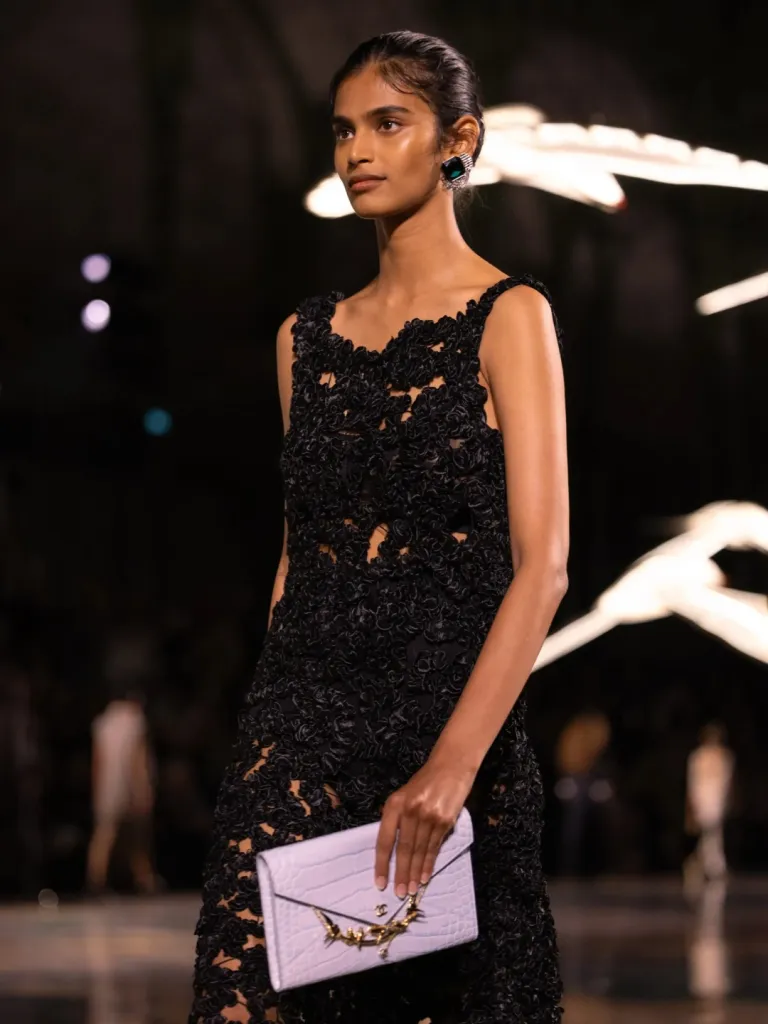 Close detail of Chanel atelier embroidery work showcasing sequins and embroidered buttons on patterned fabric