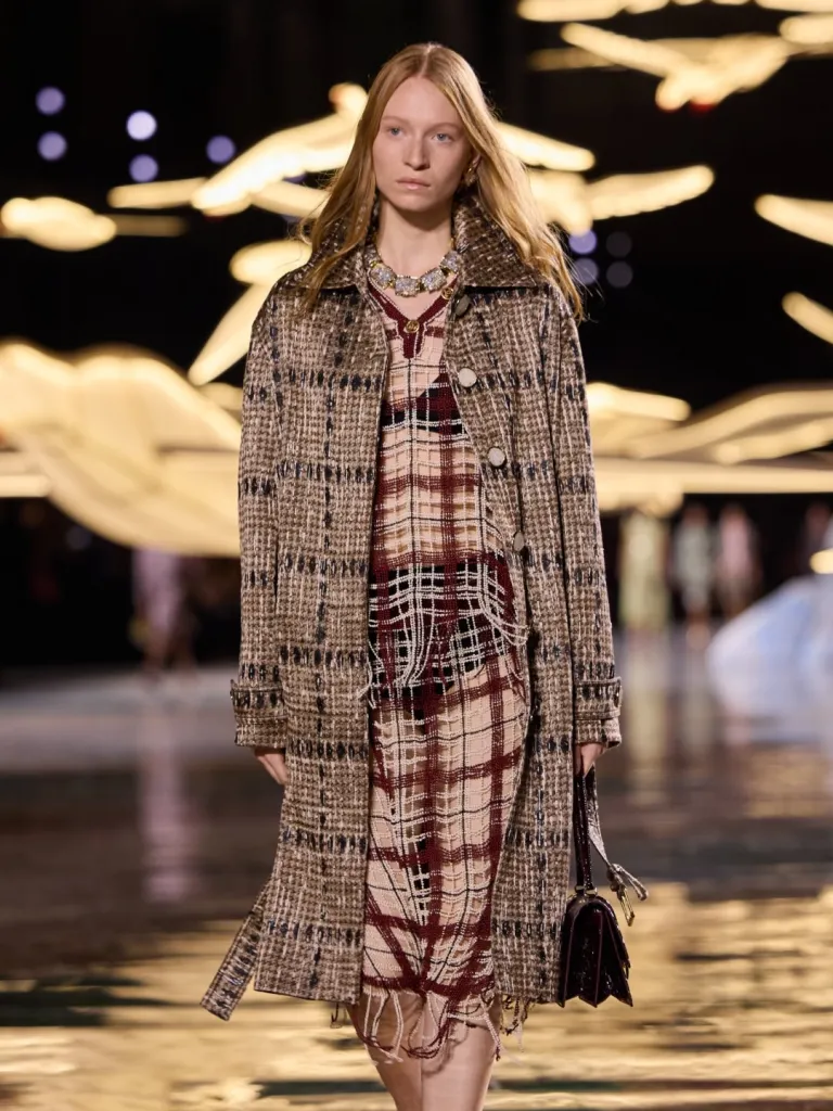 Model wearing the iconic CHANEL suit in British-inspired tweed, jacket unbuttoned against bare skin