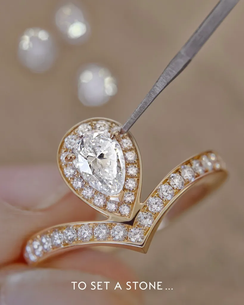 Close-up detail of the pear-cut diamond held within the delicate V-shaped rose gold embrace