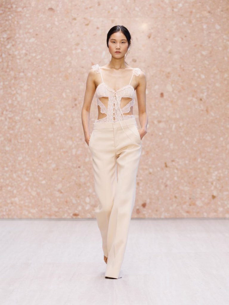 Model displaying off-shoulder cream gown with flowing panels