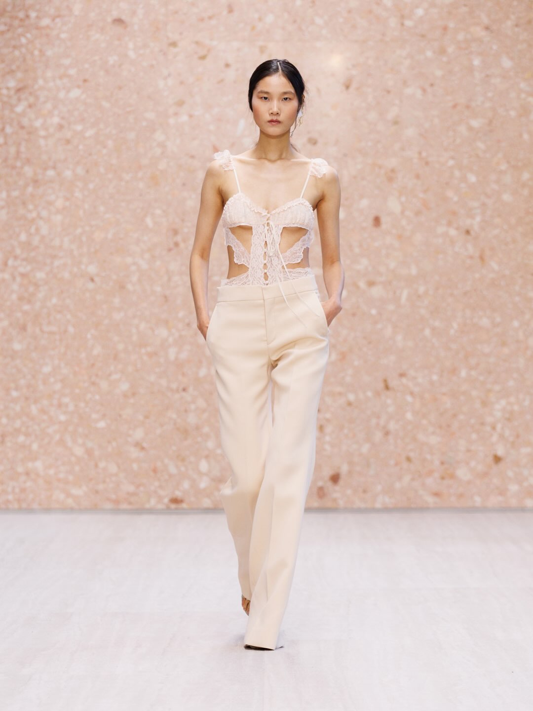 Model displaying off-shoulder cream gown with flowing panels