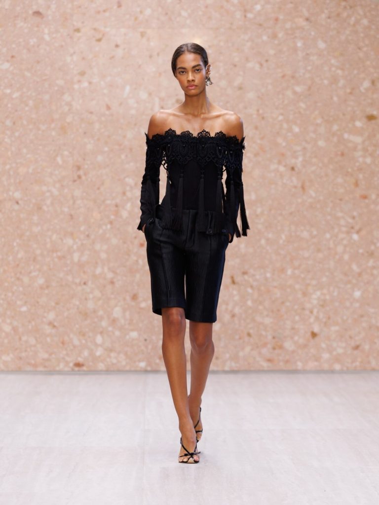 Model in elongated blush tone gown with subtle topstitching and refined construction