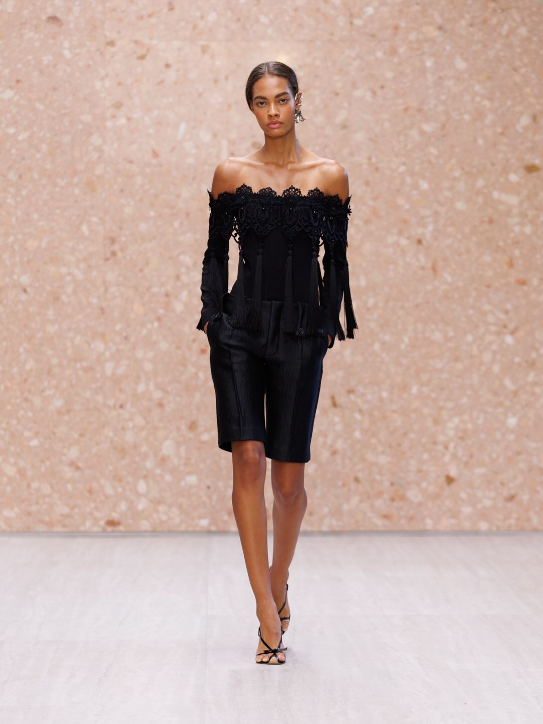 Model in elongated blush tone gown with subtle topstitching and refined construction