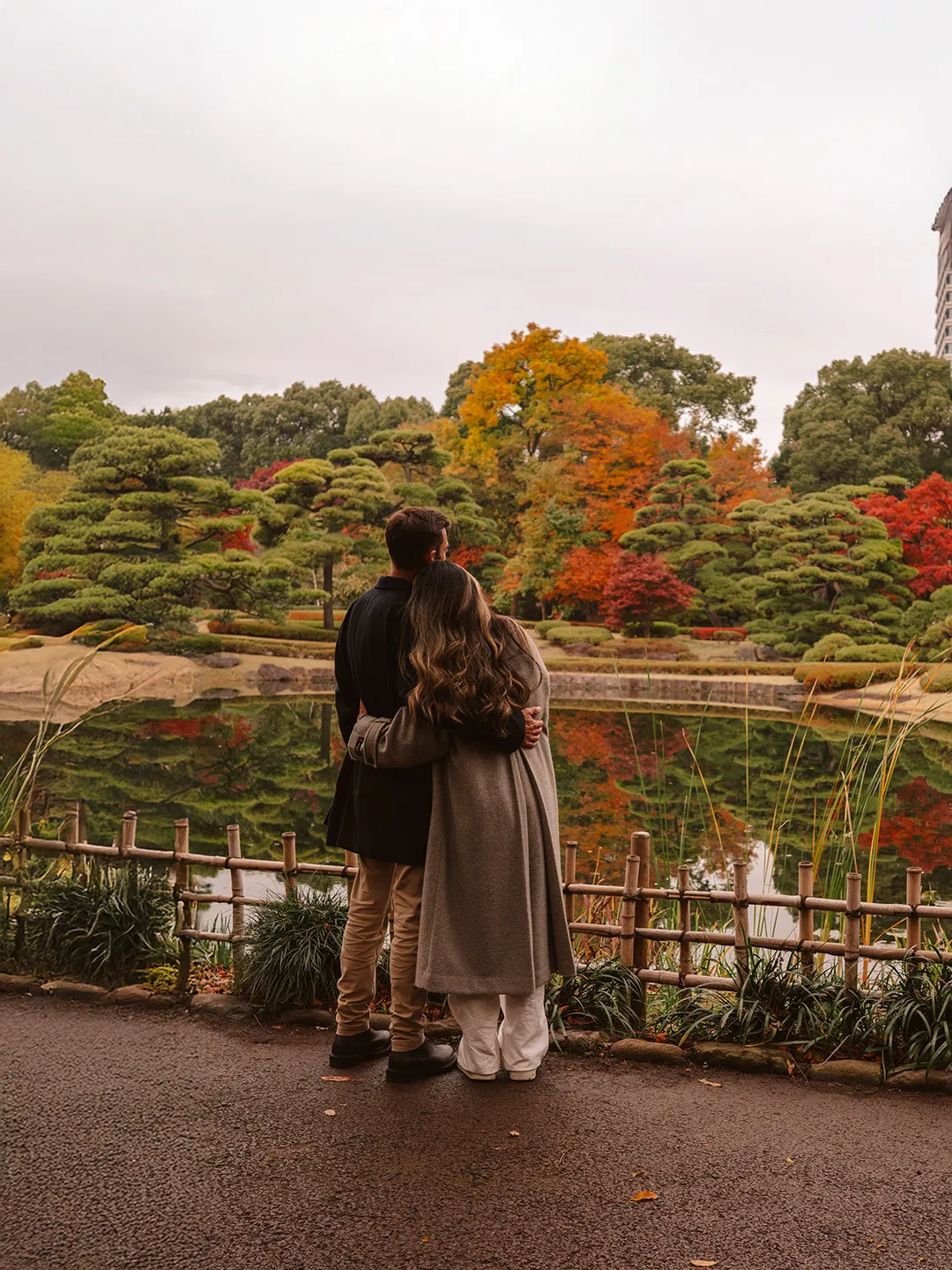 Autumn foliage glowing in vivid crimson and gold tones within a Tokyo urban park setting