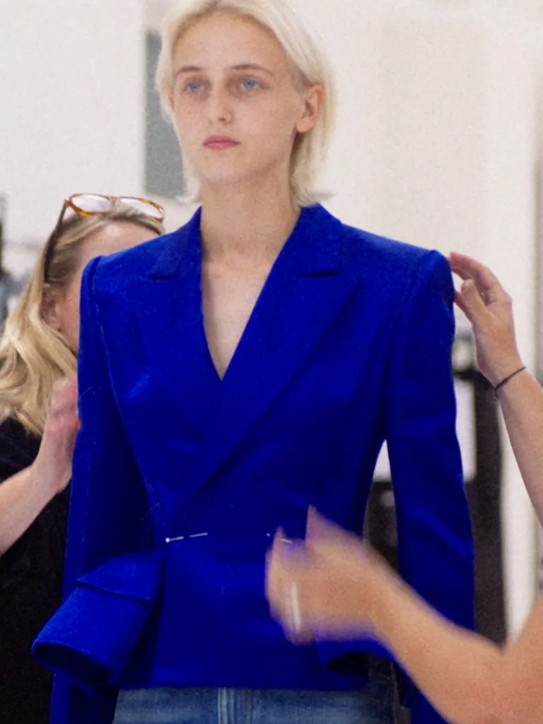Close-up of satin duchesse peplum jacket construction, highlighting the architectural silhouette and fabric sheen